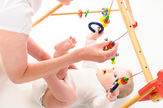 Mother and 6-month-old daughter play together on the floor with wooden toys and play bows,isolated against a white background.