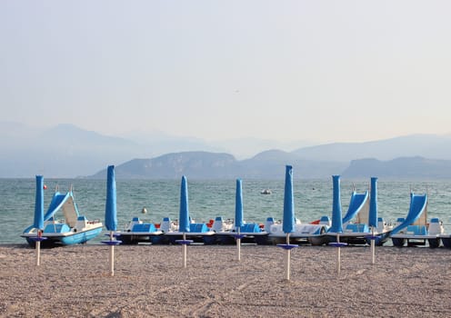 Water cycles and parasols at empty beach in the morning