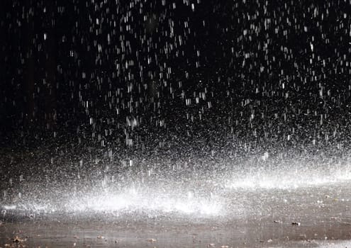 Massive rainfall on asphalt from a broken gutter under a cloudburst