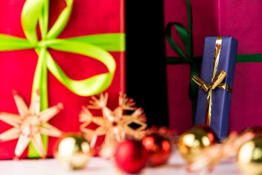 A sharply defined, blue gift with golden ribbon in the back is counterbalancing the soft forms of straw stars and Christmas bulbs in the front..