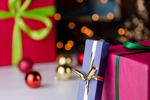 Wrapped gifts contrasting with baubles and twinkles. The golden and emerald bowknots, as well as parts of the magenta paper, are within the depth of field. .