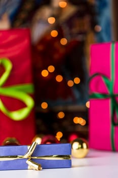 Solemnly wrapped gifts in unicolored papers. The blue present with the golden bow is within the depth of field. It is in sharp contrast with the red color fields and twinkles in the back..