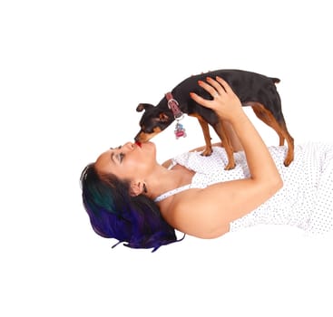 A Asian woman lying on the floor holding up her dog an giving him.a kiss, isolated on white background..