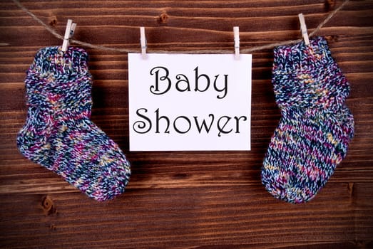 Baby Shower on a Pink Label Hanging with Socks on a Line on a Wooden Background