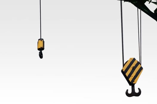 The photograph of two different winches of a lifting crane with hooks.
