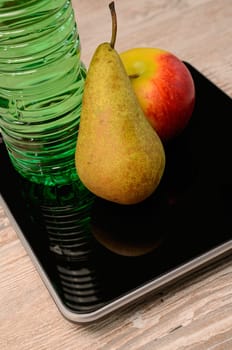 Fresh fruits and a bottle of water on a scale