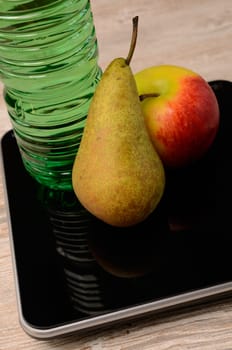 Fresh fruits and a bottle of water on a scale