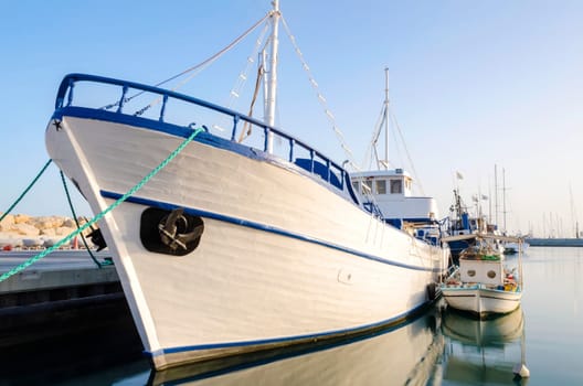 Fishing boats docked at the Limassol old port in Cyprus, next to the Marina part of the ports authority. A view of the harbor, the mediterranean sea, the water, boat and fish nets and fishing equipment.