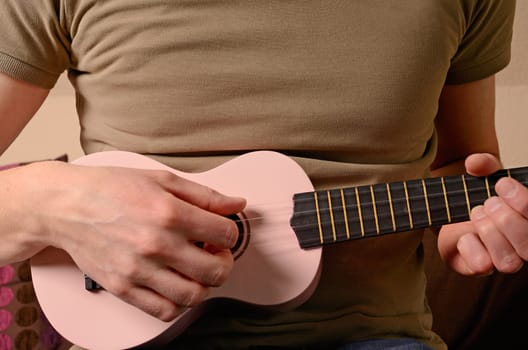 A man is playing with an ukulele