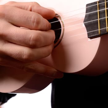 A man is playing with an ukulele