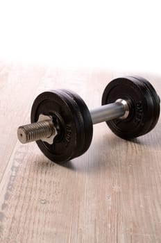Fitness background with a dumbbell on a wooden floor with space for text