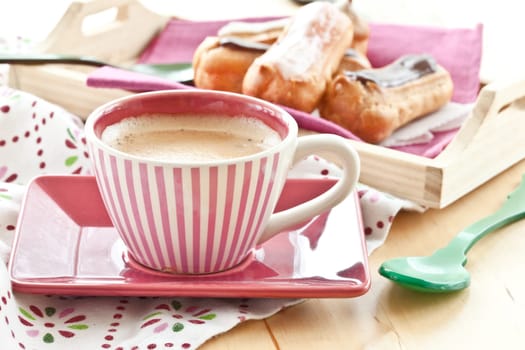 Selection of small eclairs with a cup of espresso