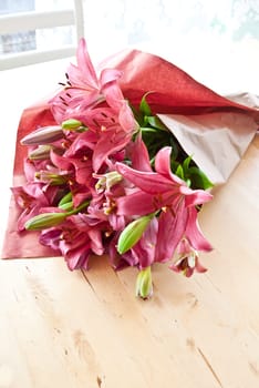 Fresh pink lilies as bouquet of flowers smashed into paper