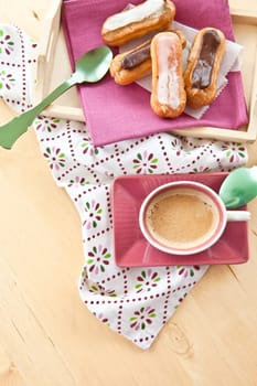 Selection of small eclairs with a cup of espresso