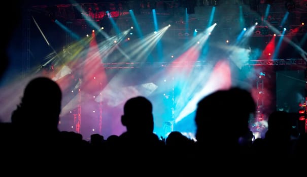 Cheering crowd in front of bright colorful stage lights