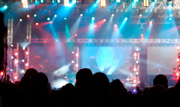 Cheering crowd in front of bright colorful stage lights