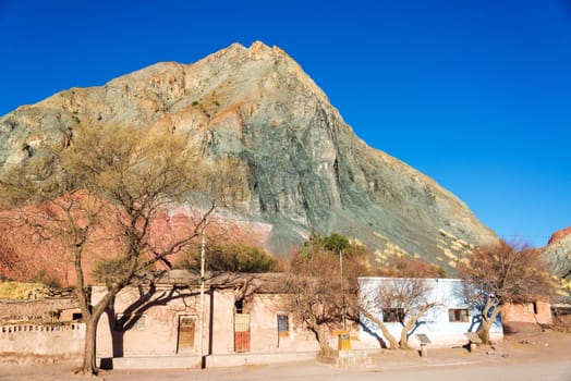 Green, orange, and red hill towering over the plaza of Monte, a small rustic town near Tupiza, Bolivia