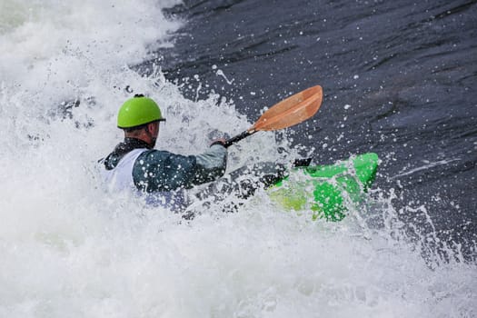 an active male kayaker rolling and surfing in rough water