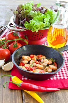 Fried shrimp with chilli in cast iron pan and fresh salad