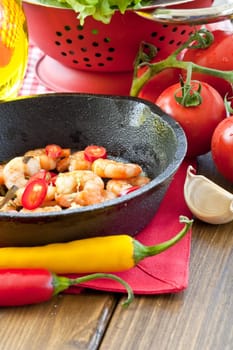 Fried shrimp with chilli in cast iron pan and fresh salad