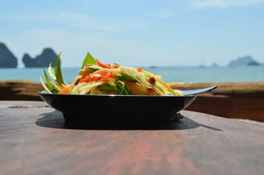 som tam thai, green papaya salad with an ocean background at Tonsai beach