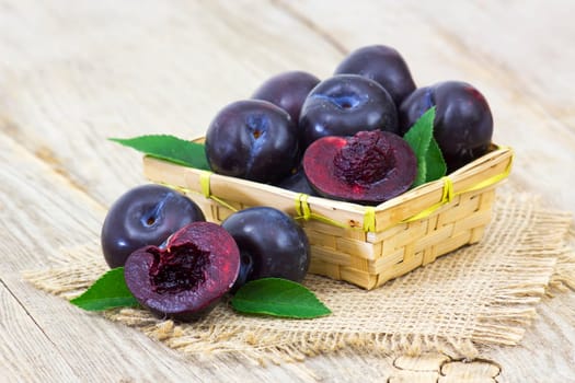 fresh plums in a basket on old wooden background