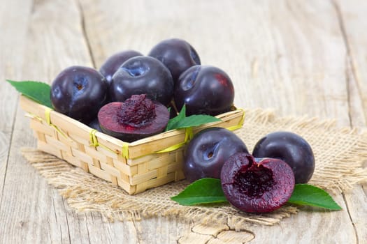 fresh plums in a basket on old wooden background