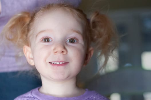 Pretty little redhead girl with a cute expression looking at the camera with parted lips and an amused look in her eyes