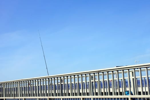 The photograph of a bridge railing with a leaning fishing rod.
