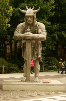 Potsdam Babelsberg,Germany - August 11,2012: A child and a wheelchair user pass the sculpture of a barbarian at the Babelsberg Film Park on August 11,2012 in Potsdam,Germany.