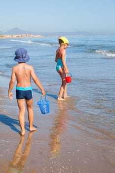 Cute kids looking for sea shells on the beach