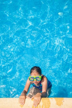 Happy girl with goggles relaxing in swimming pool