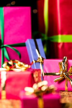 Six presents prepared for any gift-giving occasion. Focus is on the golden bow knot around the small magenta box on the right..