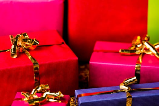 Tightly framed shot of plain-colored gift boxes in magenta, crimson and blue. Shallow depth of field. Background for any gift-giving occasion..