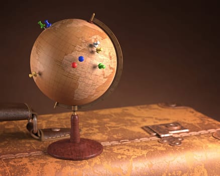 Old globe with pins marking the route of the trip on top a vintage suitcase.