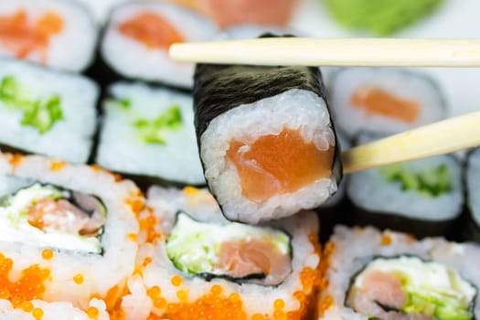 Closeup view of a set of maki sushi. One piece of sushi is in the sushi bars