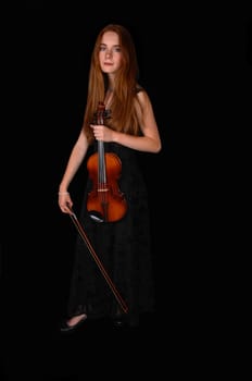 A pretty woman standing for black background holding her violin..