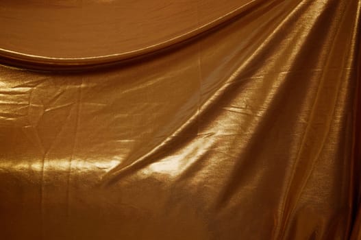 A wrinkled gold fabric background, draped and filling frame.