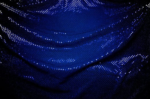 A dramatically draped piece of blue sequined fabric typically used to make dancer's costumes fills the image.