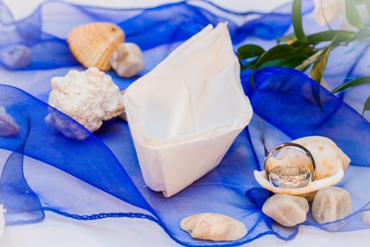 wedding rings with paper boat on blue ribbon
