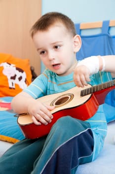 wounded in the left hand with bandage boy at shot in home with guitar