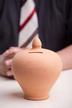 pottery clay moneybox means savings are needed and this office worker, maybe a clerk or an accountant, knows it very well