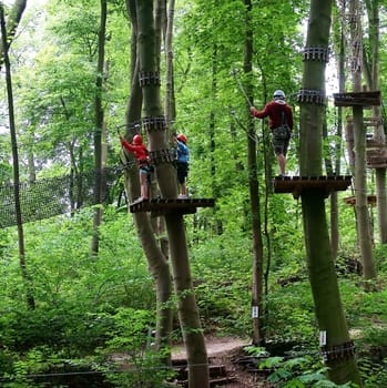 Schwerin,Germany – August 09,2012: The Schwerin climbing forest with obstacle course in the middle of trees and people in protective gear on August 9,2012 in Schwerin.