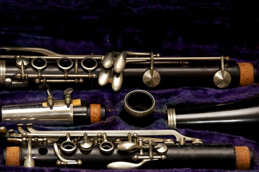 Parts of a clarinet are stored in blue lined case.