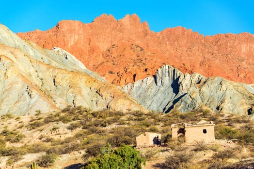 A ruined building at the base of dramatic colorful hills in the small town of Quiriza near Tupiza, Bolivia