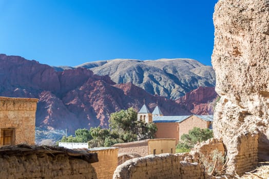 Church set against a dramatic cliff and beautiful red hills in the small town of Espicaya near Tupiza, Bolivia
