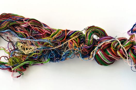 Tangled colorful sewing threads on white background.