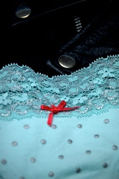 A pair of woman's blue polka dot lace panties with pink bow is draped upon a man's black leather jacket.