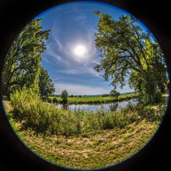 Round fisheye takeus of river with its vegetation and the sun.