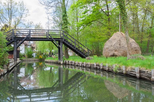 Small wooden bridge over a canal and a haystack typical of the area